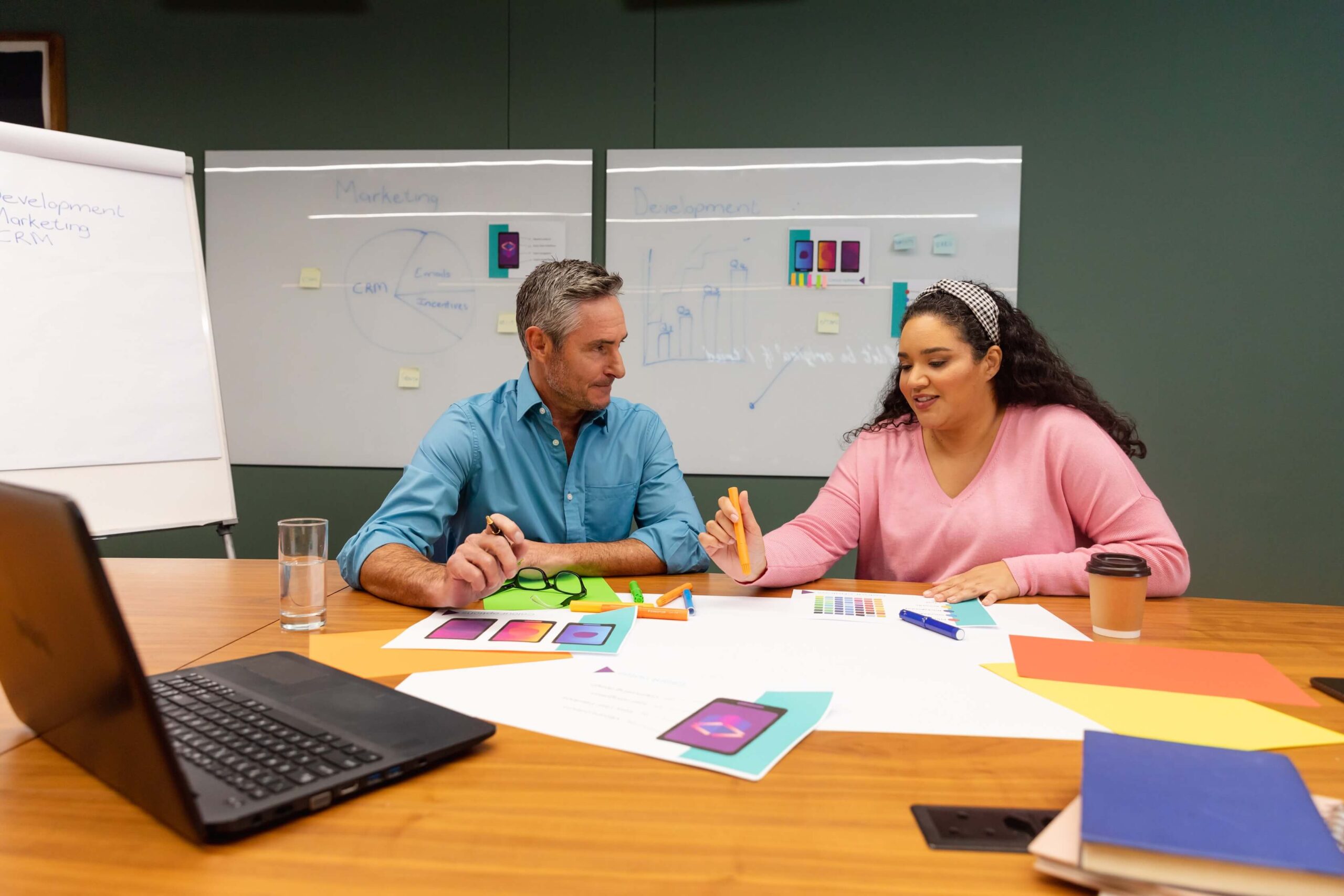 A man and woman sit at a table with a laptop, collaborating on a project for Innovation Behavior Services.
