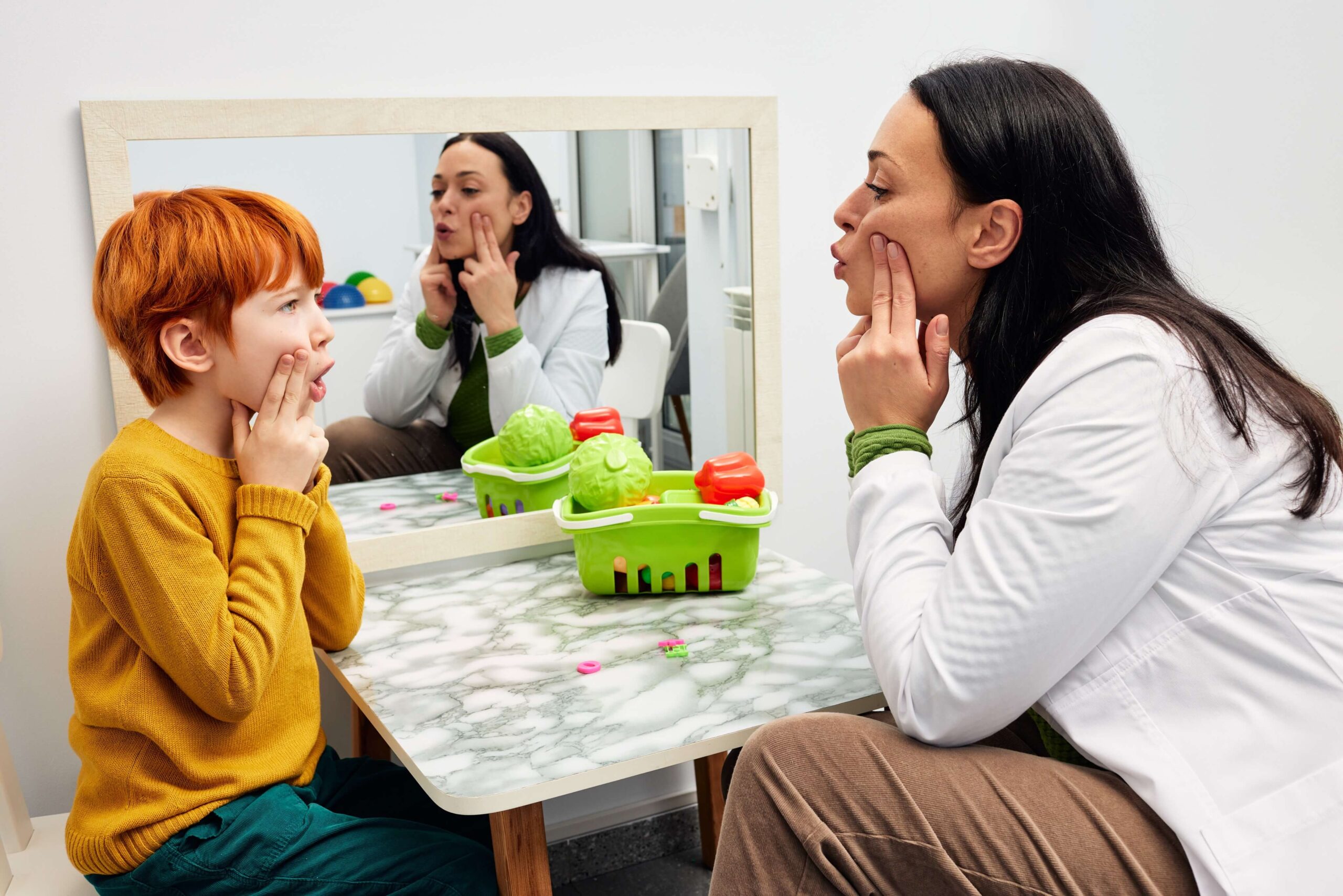 Child working on speech exercises during autism therapy session with therapist.