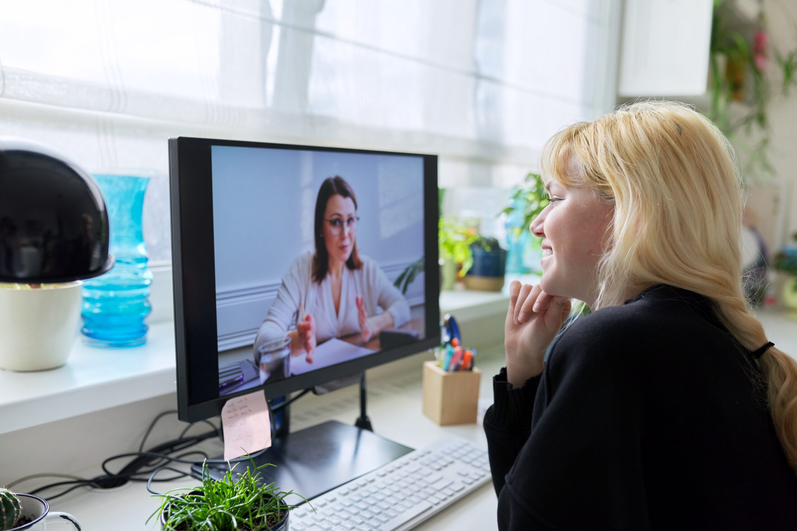Therapist and teenage girl engaging in a virtual therapeutic consultation via computer screen.