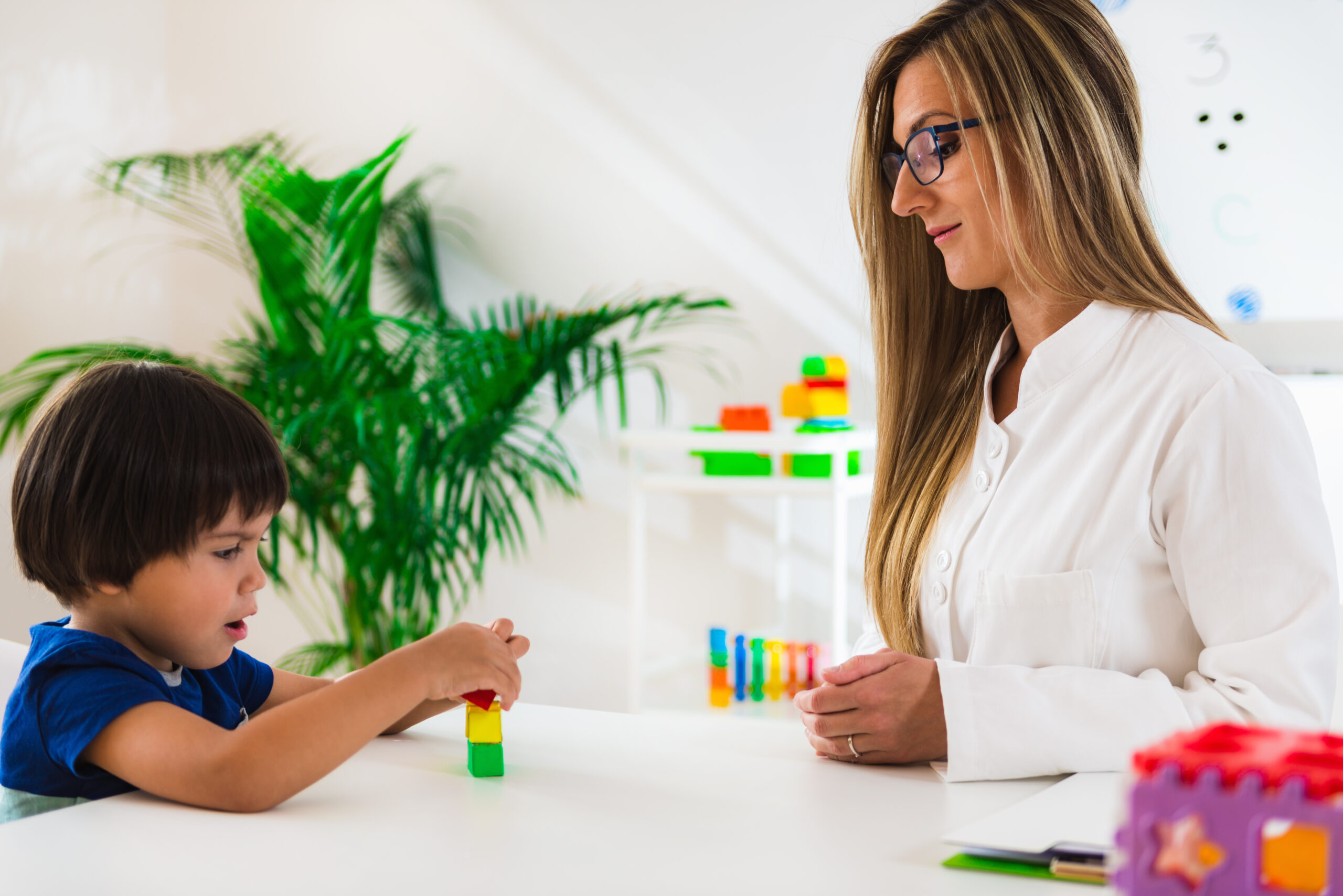Therapist engaging child in ABA therapy session using building blocks to teach new skills.